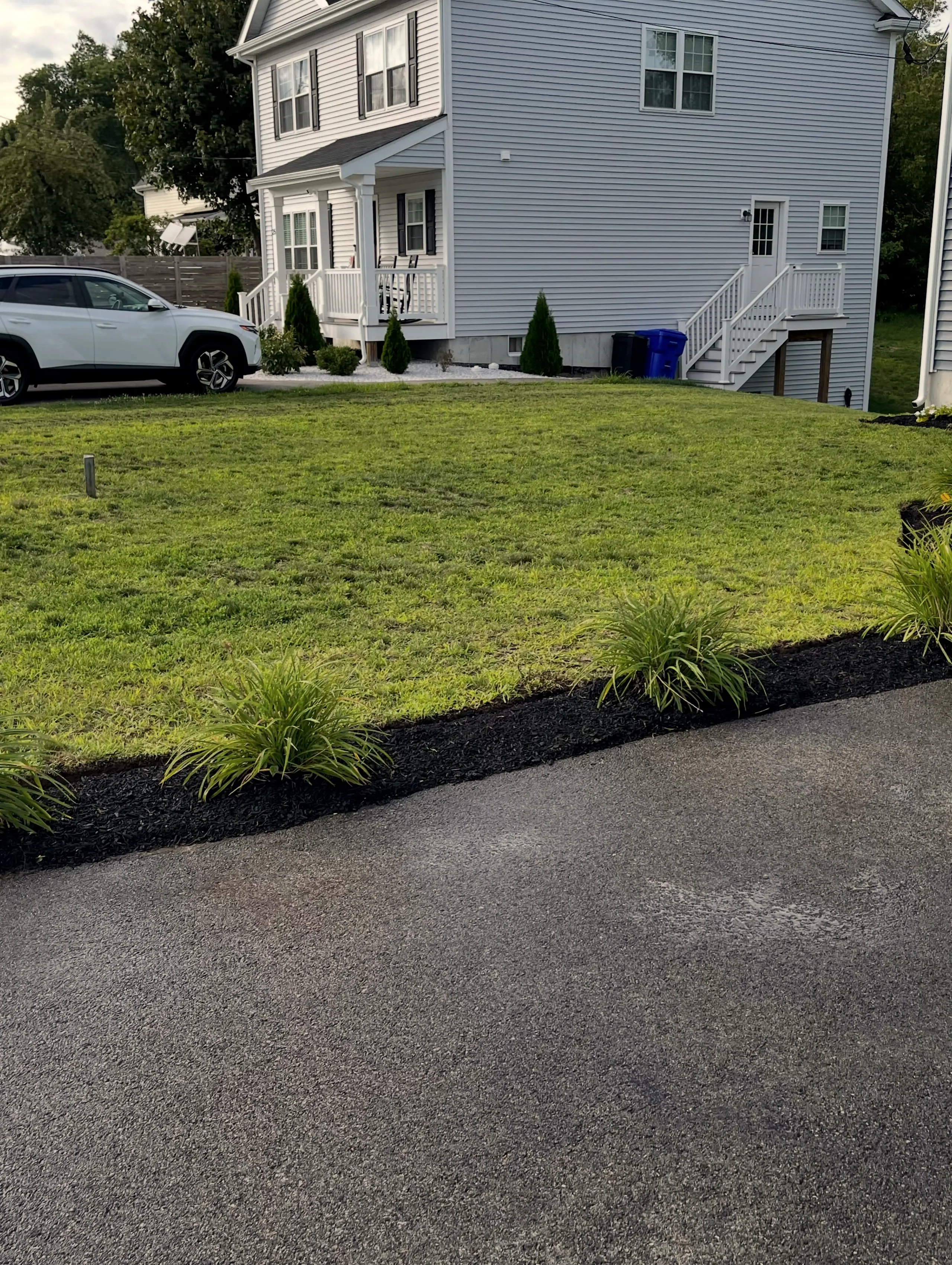 Lawn and black-mulch planting bed along the driveway of a new house