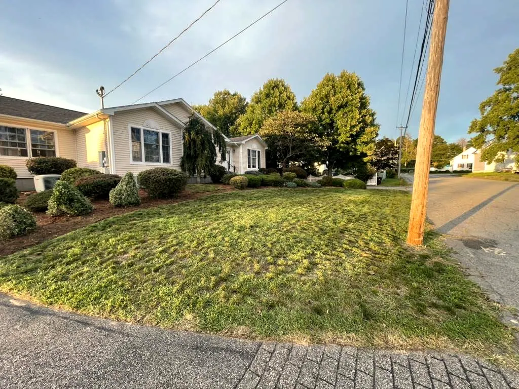 Mowed lawn and pruned shrubs at a ranch house, from the street