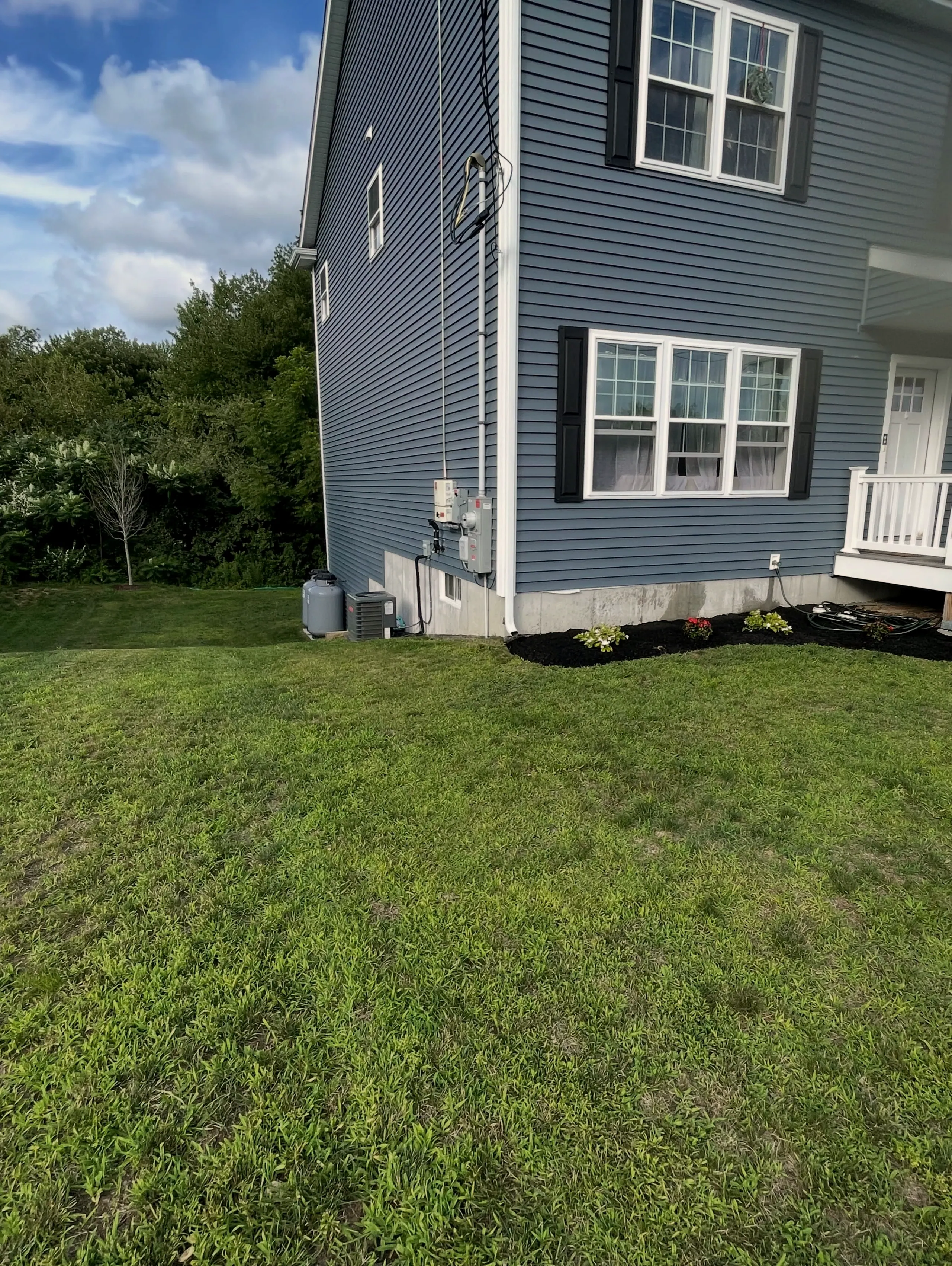 Side lawn with a mulched foundation bed along a blue house